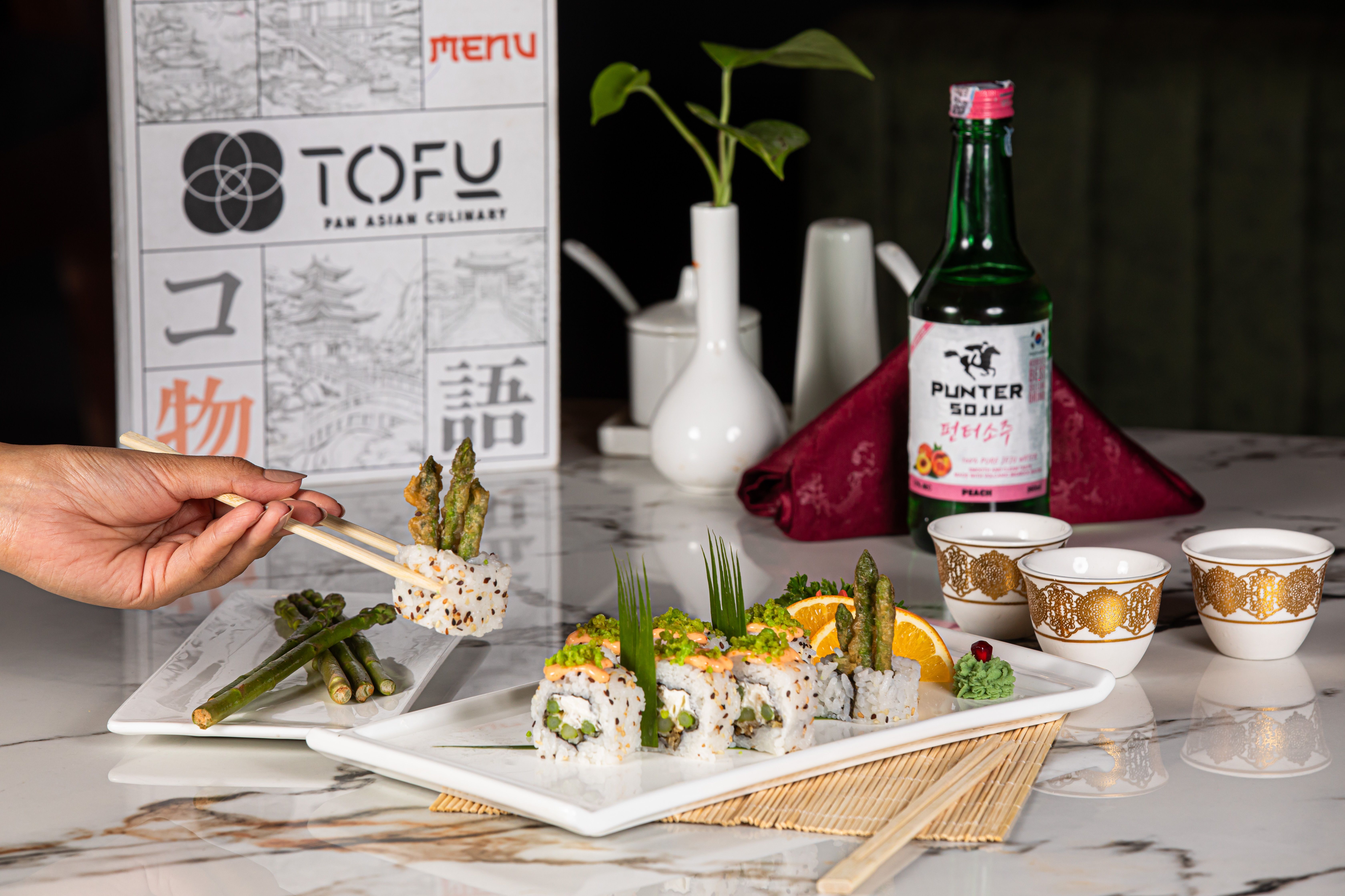 ingyenes Sushi spárgával és citrusfélékkel, sojuval párosítva, kifinomult ázsiai étkezési környezetet mutat be. Stockfotó