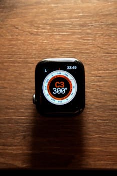Smartwatch displaying compass direction at 300 degrees on a wooden surface.