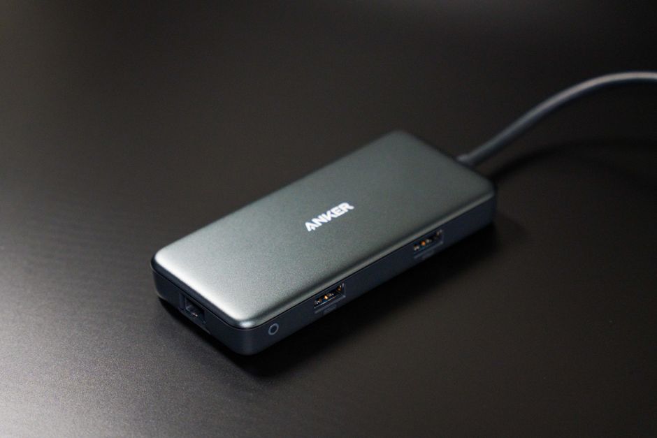 어두운 책상 위에 놓인 소형 USB-C 허브. 눈에 보이는 USB 포트가 달려 있습니다.