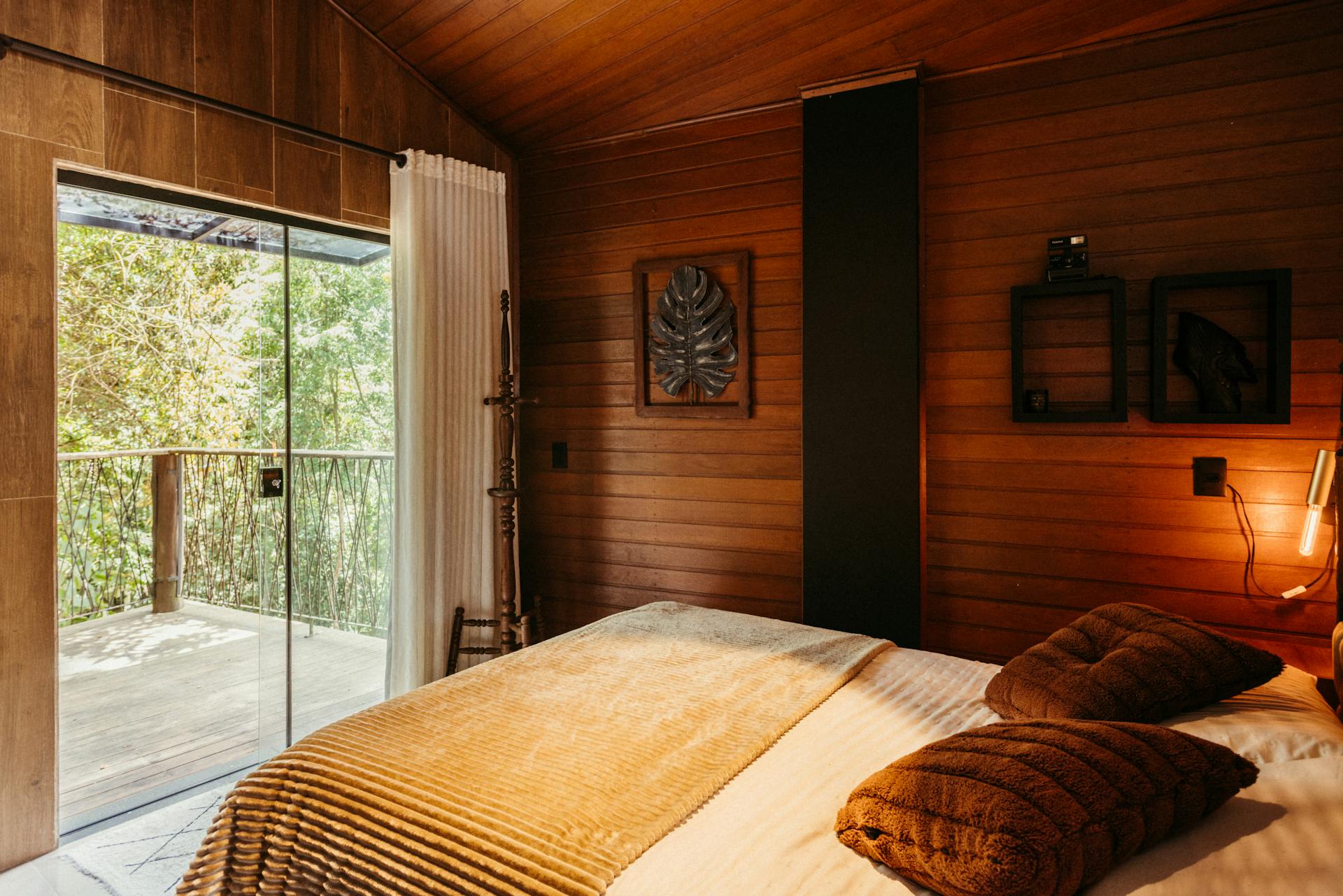 Warm and inviting wooden bedroom with a balcony view of the lush forest in Santa Teresa, Brasil.