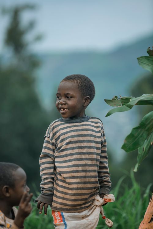 Free A joyful child in a striped shirt smiles brightly in a lush rural landscape. Stock Photo