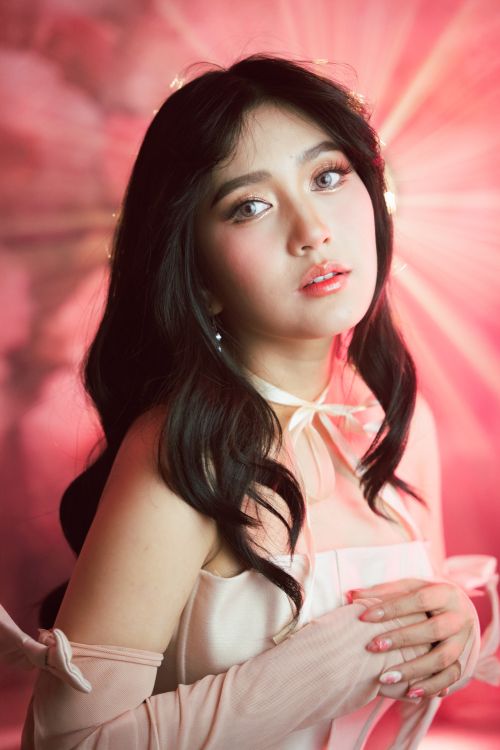 Free A captivating portrait of a woman in soft pink lighting, evoking elegance and grace. Stock Photo