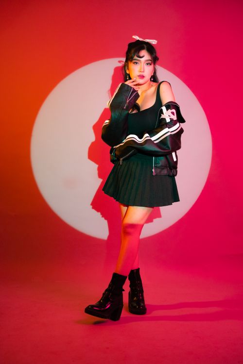 Free Stylish young woman posing against a bold red backdrop with dramatic lighting. Stock Photo