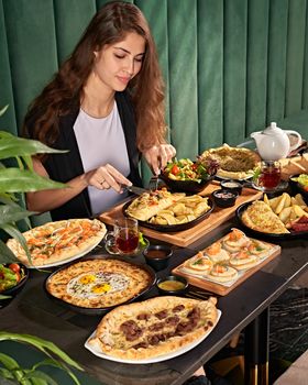 Young woman dining on a variety of delicious dishes in a cozy cafe ambiance.