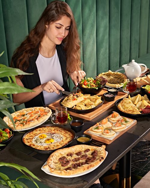 Free Young woman dining on a variety of delicious dishes in a cozy cafe ambiance. Stock Photo