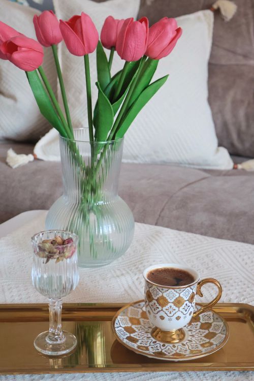 Free A cozy coffee setup with tulips and decorative cup on a gold tray. Stock Photo