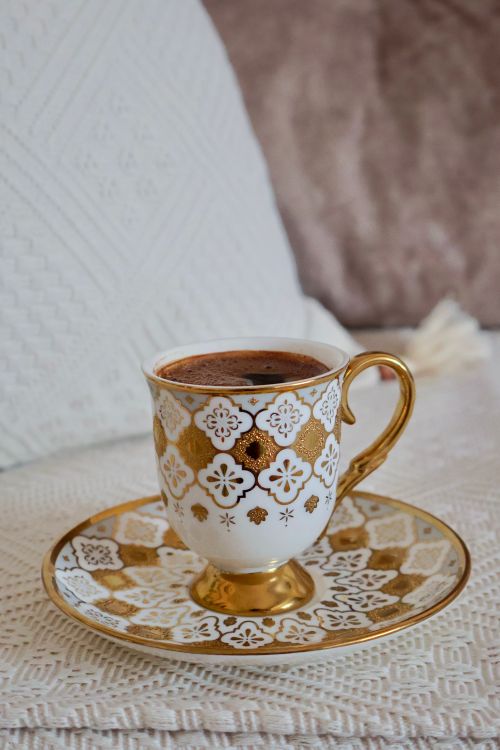 Free A beautifully patterned coffee cup with gold accents on a matching saucer. Stock Photo