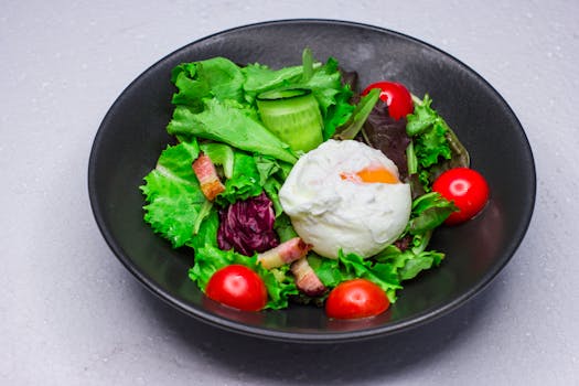 Fresh garden salad with a poached egg, cherry tomatoes, and bacon, perfect for a healthy meal.