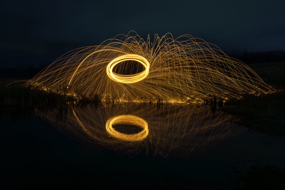 Captivating long exposure of wire wool spinning over water creating brilliant light patterns.