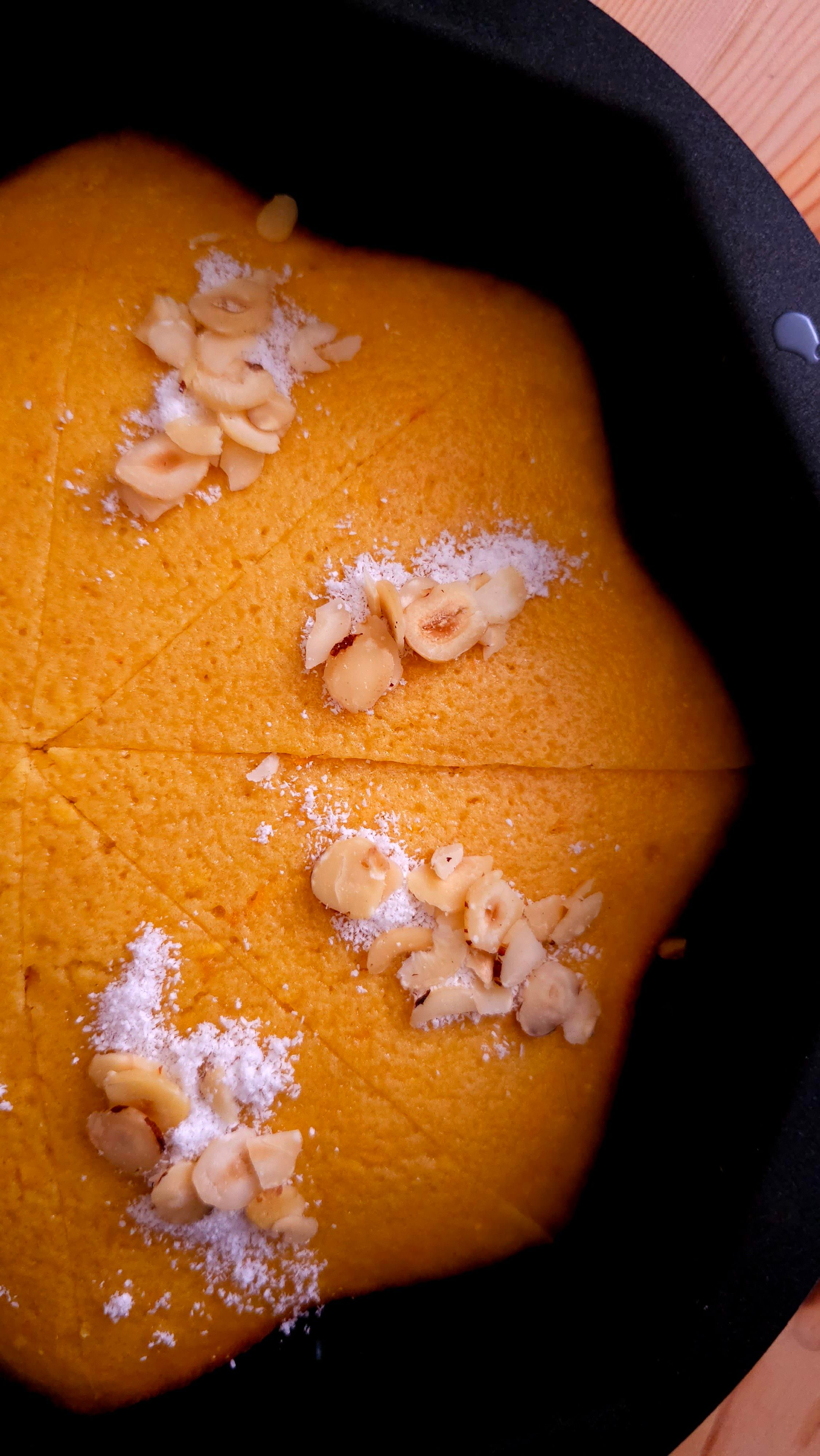 Close-up of freshly prepared halva topped with nuts and powdered sugar, ready to serve.