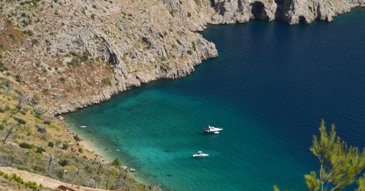 Turquoise water and rocky cliffs along the Croatian coast from above.
