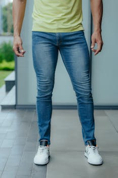 Man wearing stylish blue jeans and sneakers indoors, showcasing casual fashion style.