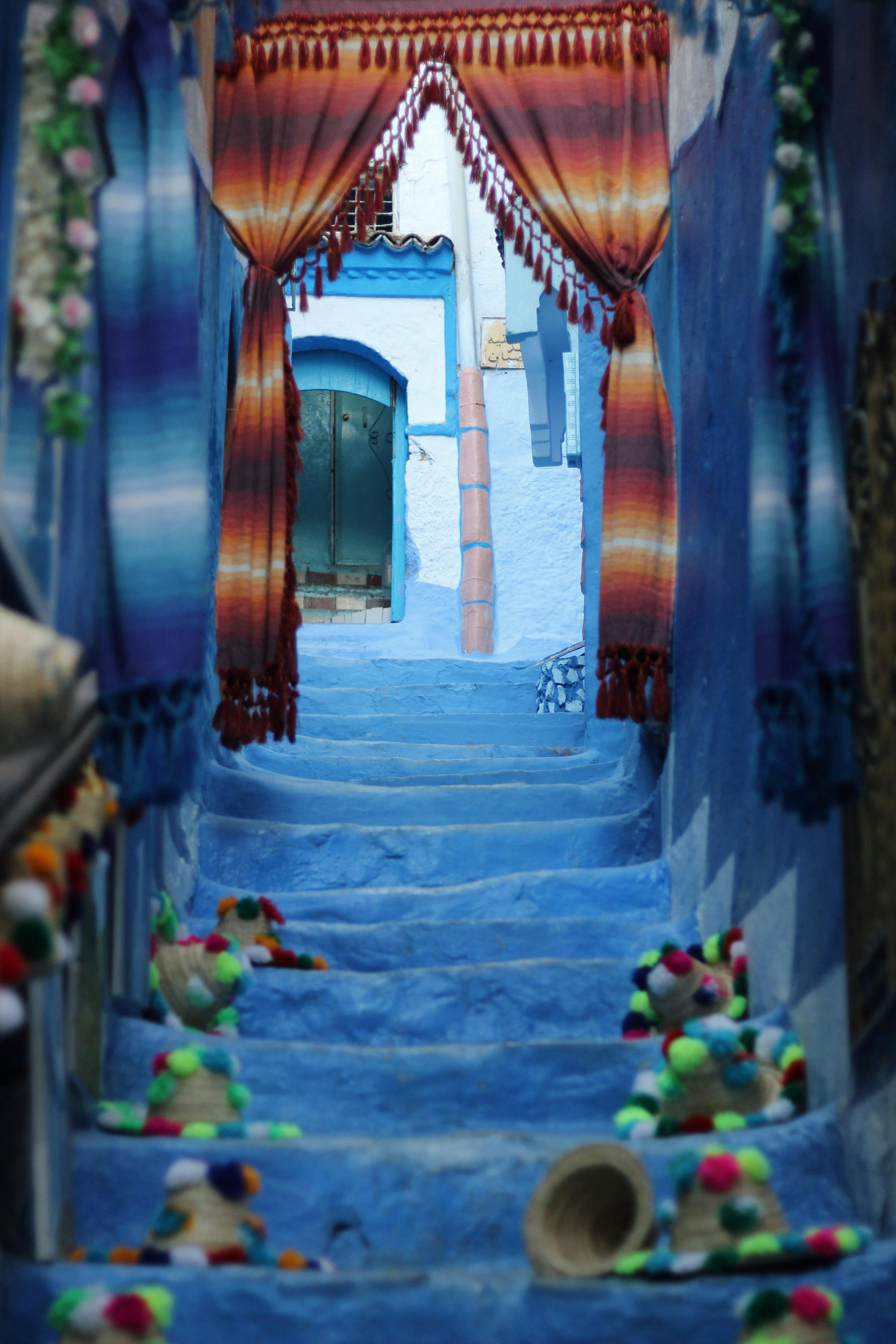 Vivid blue stairs adorned with textiles and decor in the picturesque streets of Chefchaouen, Morocco.