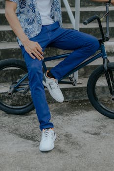 Person sitting on a BMX bike in a casual outfit, showcasing modern urban style.