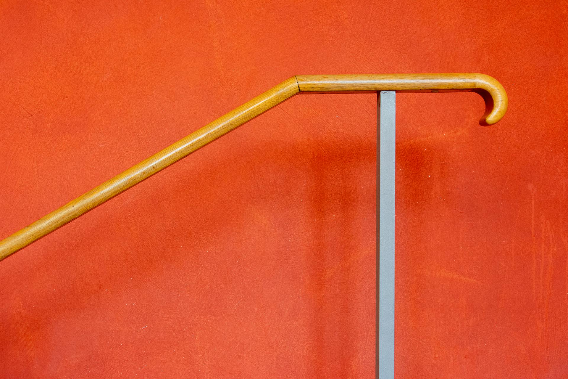 Minimalist image of a wooden handrail on a bright orange background. Ideal for design and architectural themes.