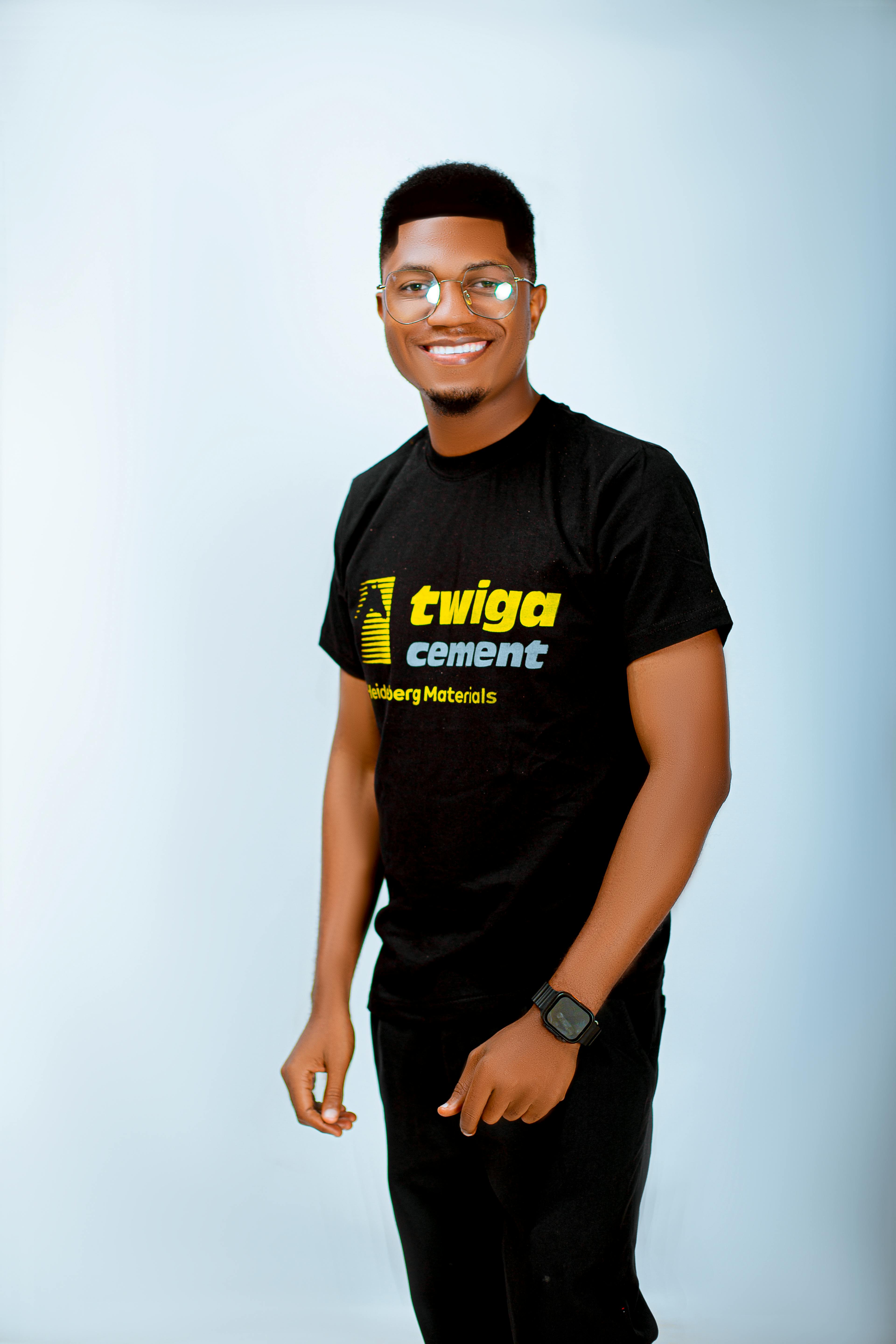 Portrait of a smiling man wearing a black Twiga Cement T-shirt and glasses.