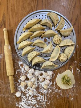 A top view of various dumplings and ingredients on a kitchen surface.