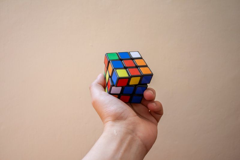 Hand holding a colorful Rubik's Cube representing problem-solving and strategy