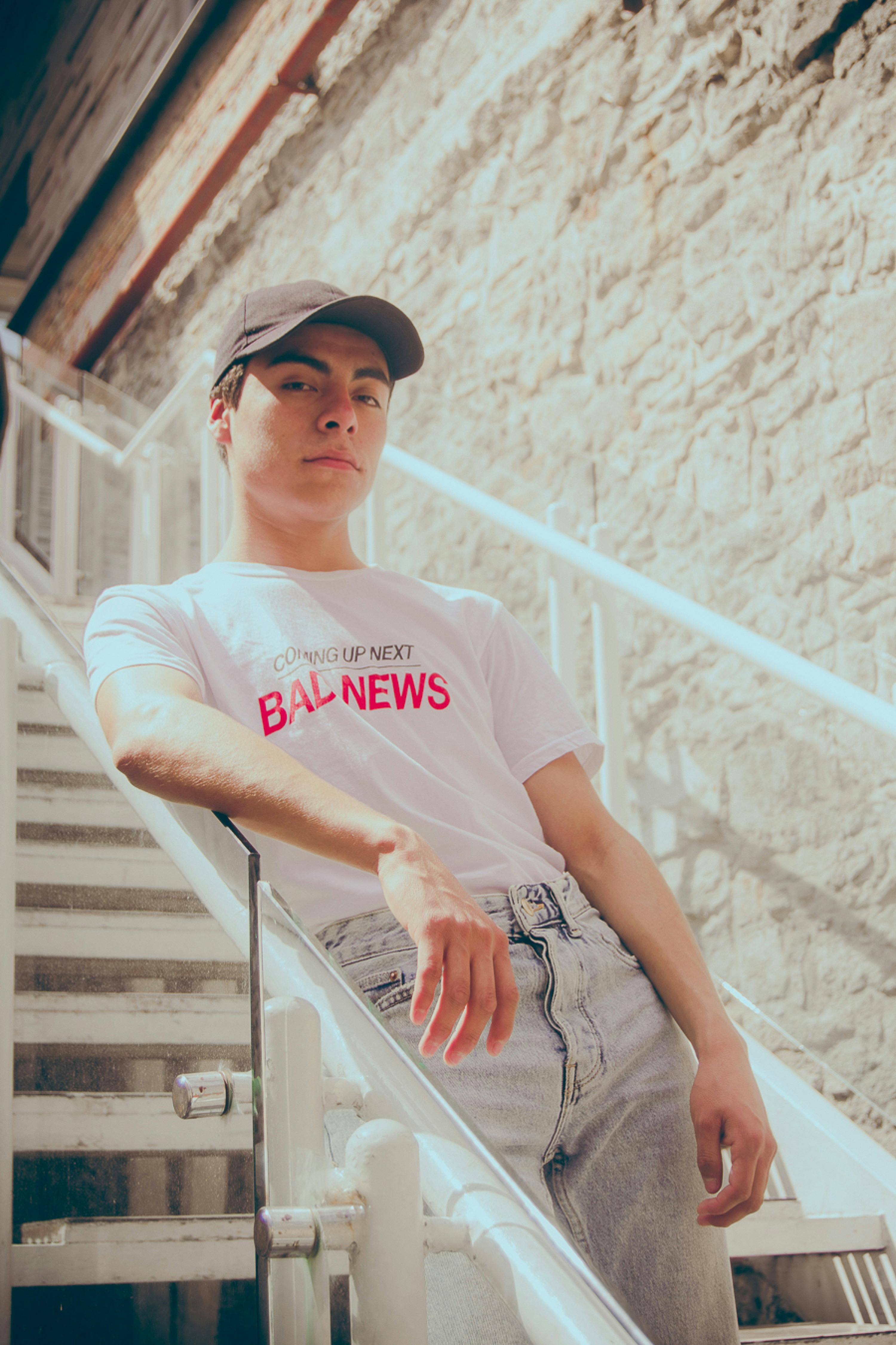Young man in casual attire on outdoor staircase under bright daylight.