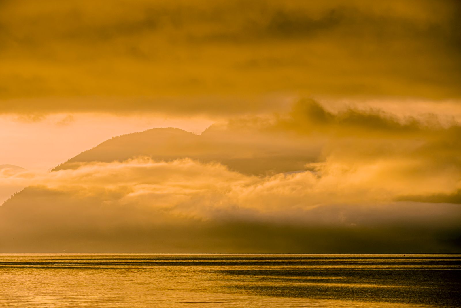 Golden sunrise over misty mountains and calm waters