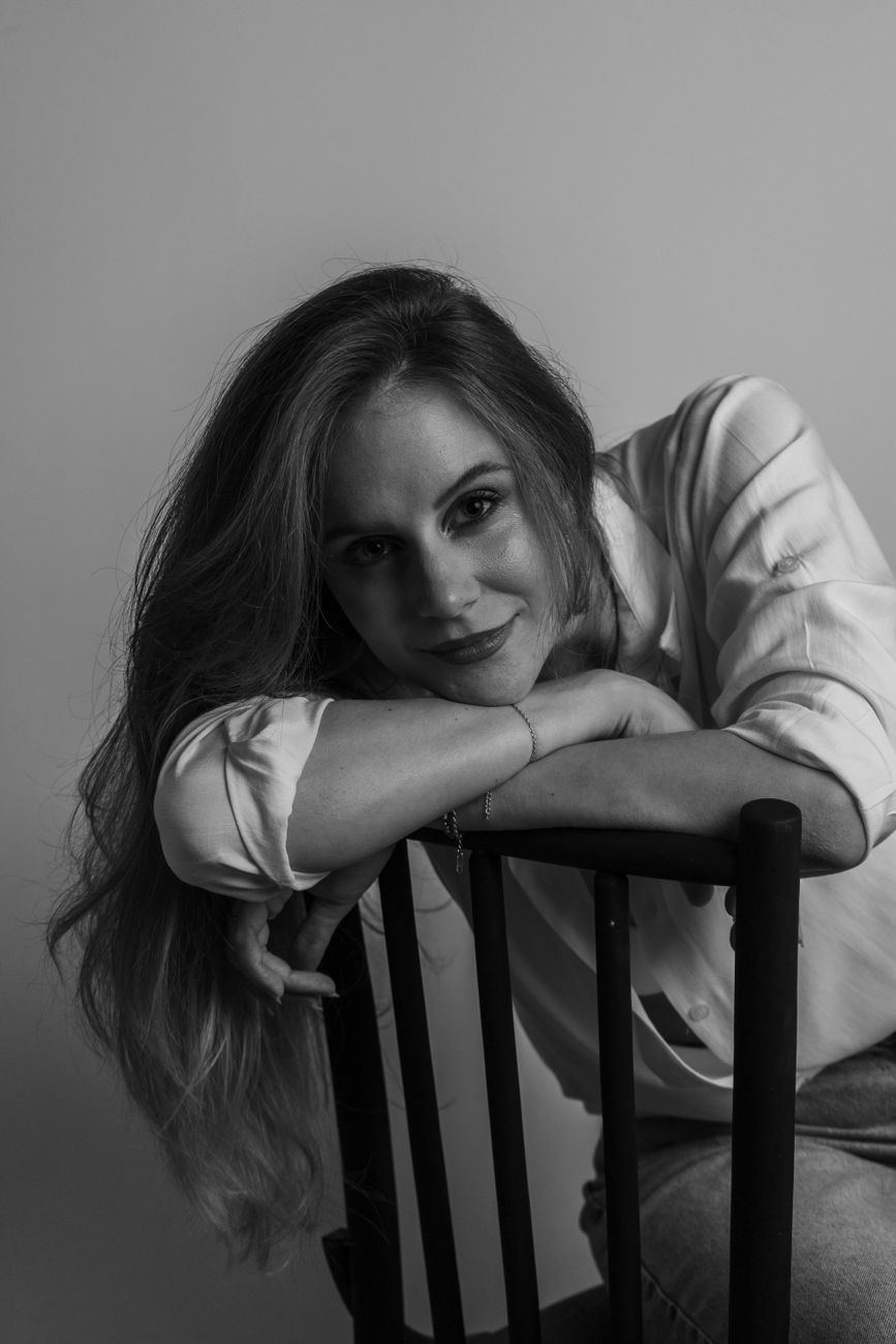Retrato clássico em preto e branco de uma mulher apoiada em uma cadeira, perfeito para branding profissional.