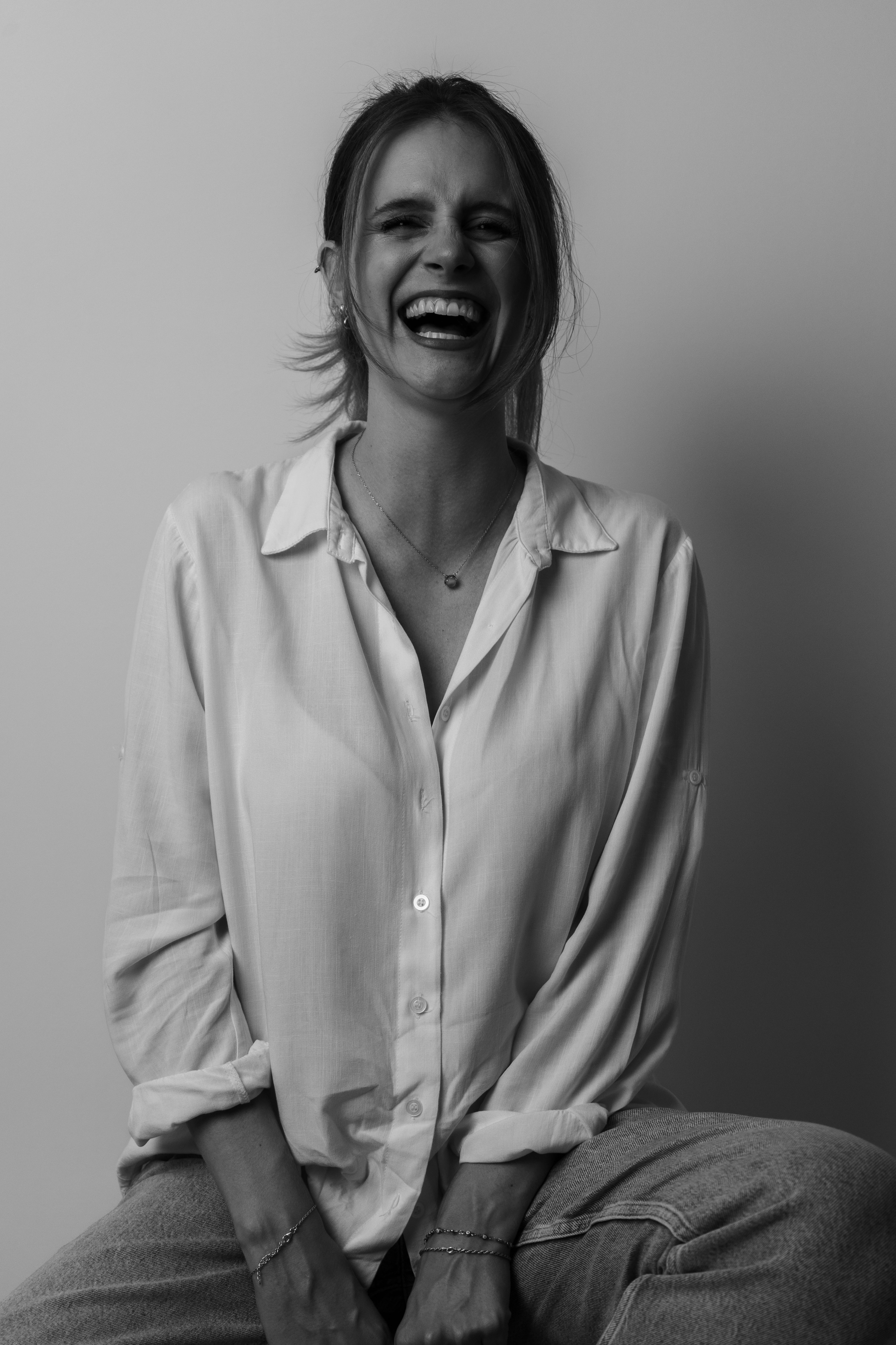 A joyful young woman smiling in a stylish monochrome portrait, captured indoors.