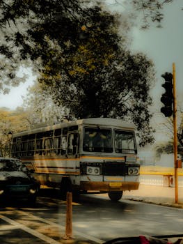 A classic Indian bus on a city street in GA, India, surrounded by lush greenery.