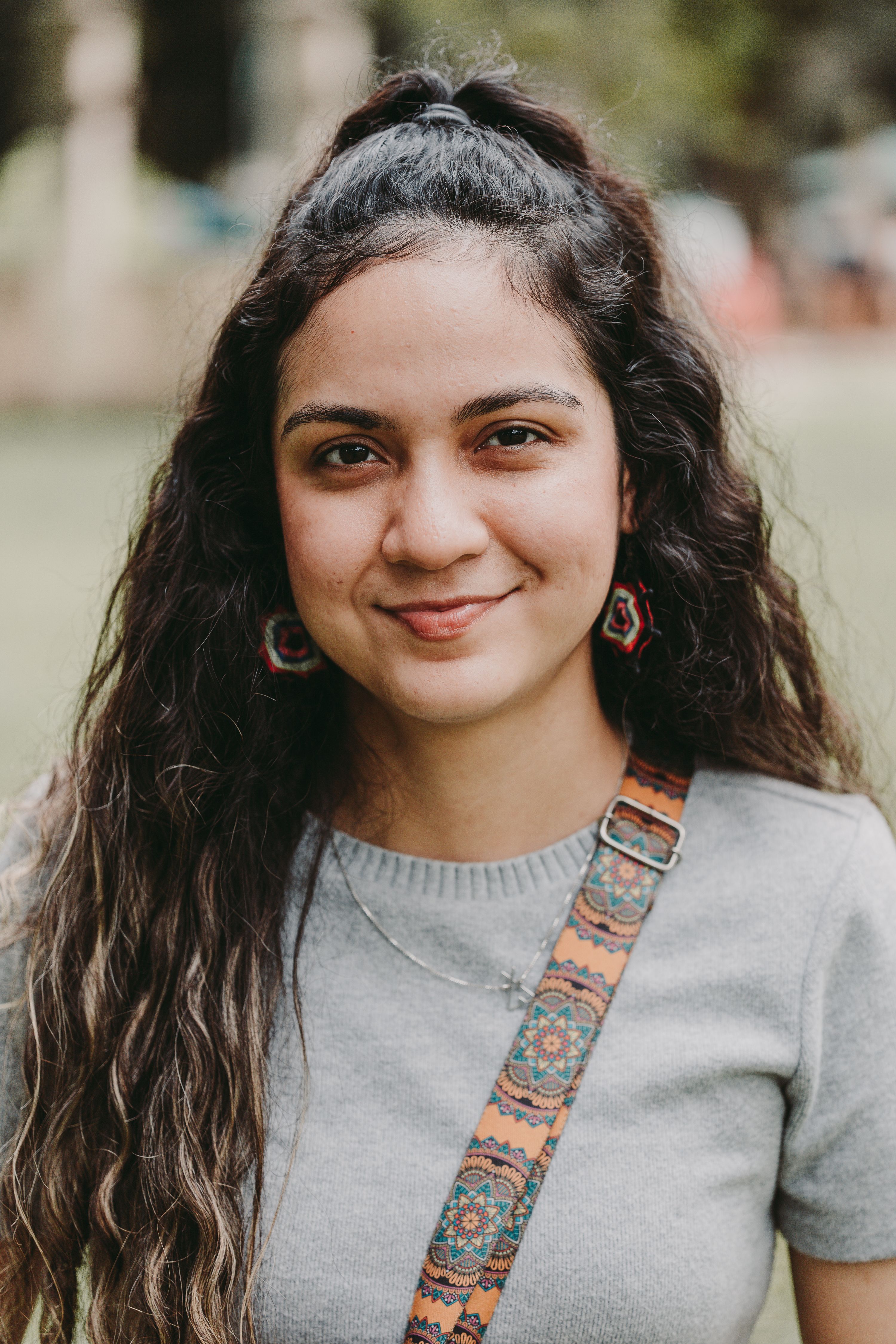 Smiling young woman with long hair and colorful earrings in a park in Belém, Brazil.