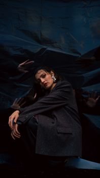 A moody portrait of a woman in a stylish suit against a textured backdrop.