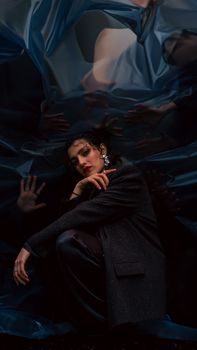 Moody artistic portrait of a woman surrounded by reflections and shadows.