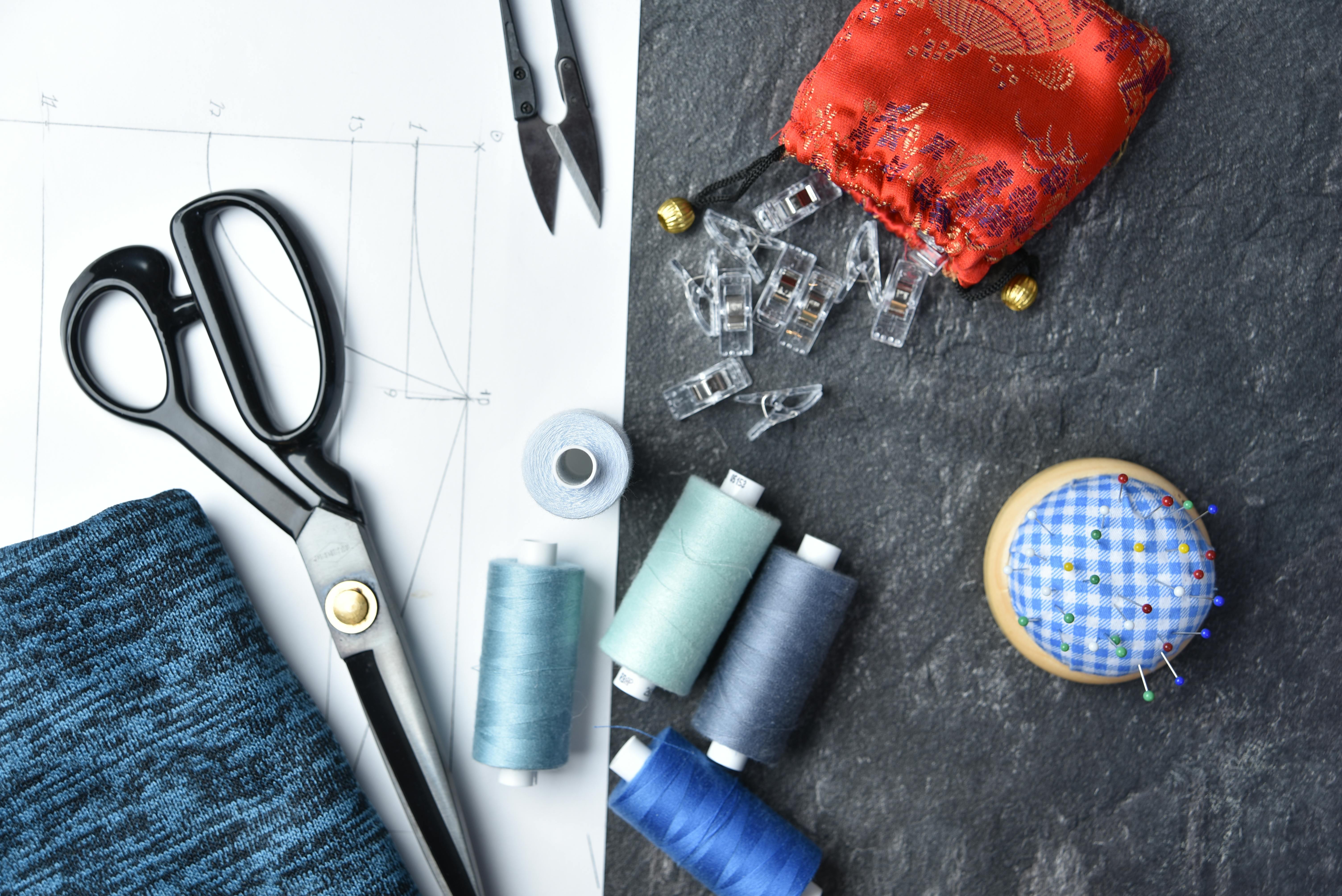 Flat lay of sewing supplies and tools, featuring threads, scissors, and fabric. — Maynard Longarm Quilting