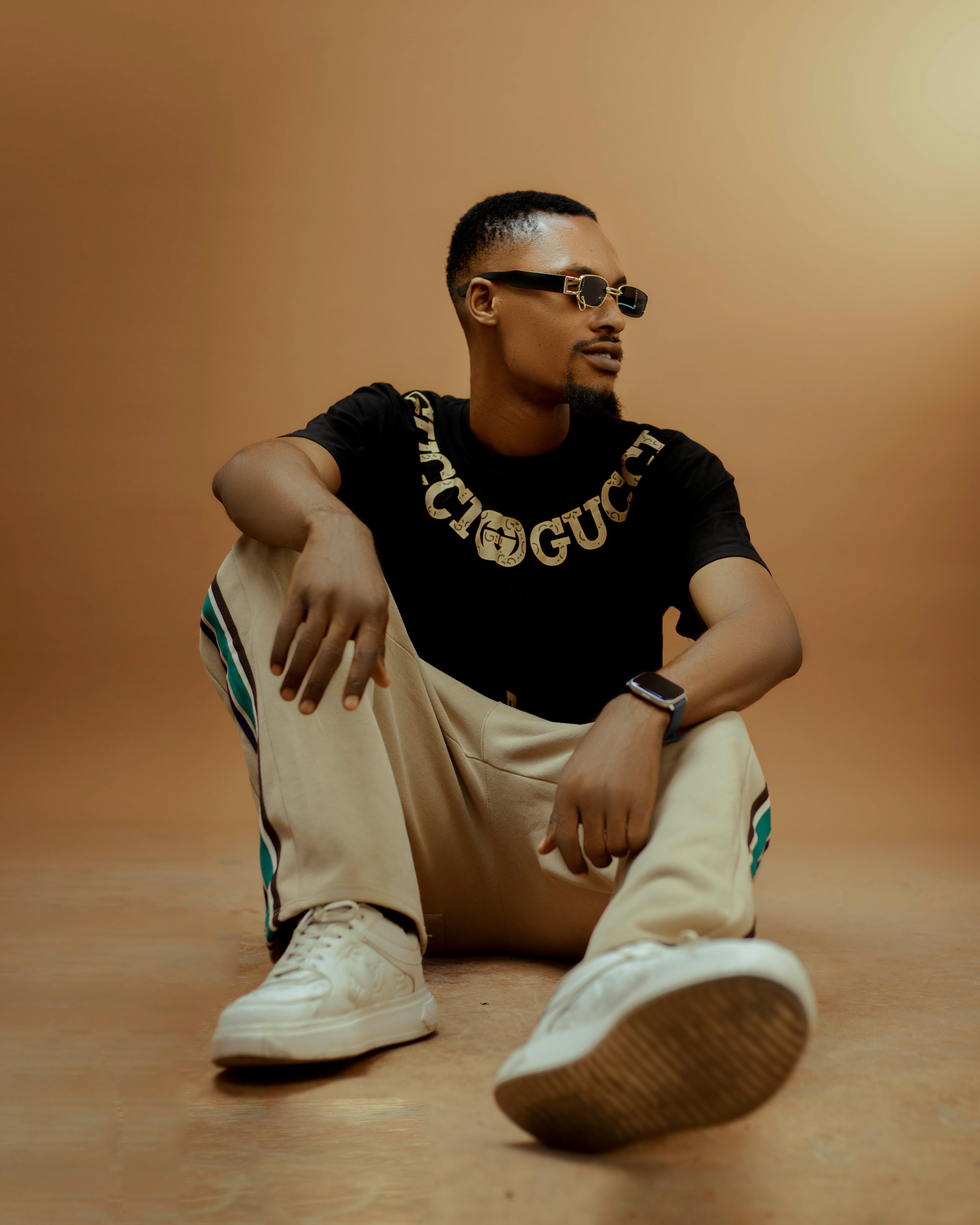 Trendy man in urban fashion with sunglasses sitting on floor.