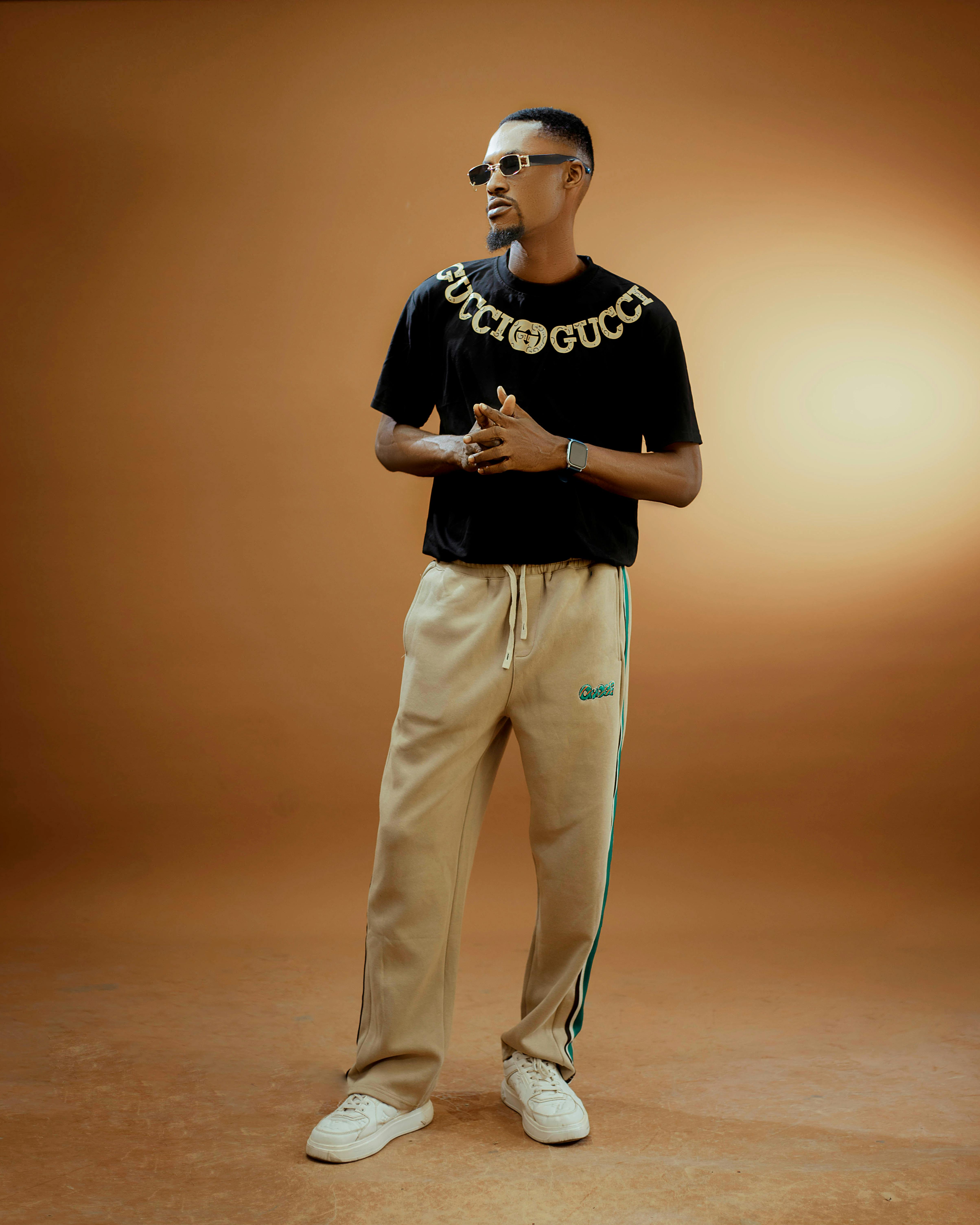 Fashionable adult in trendy clothing against a warm, studio-lit background.