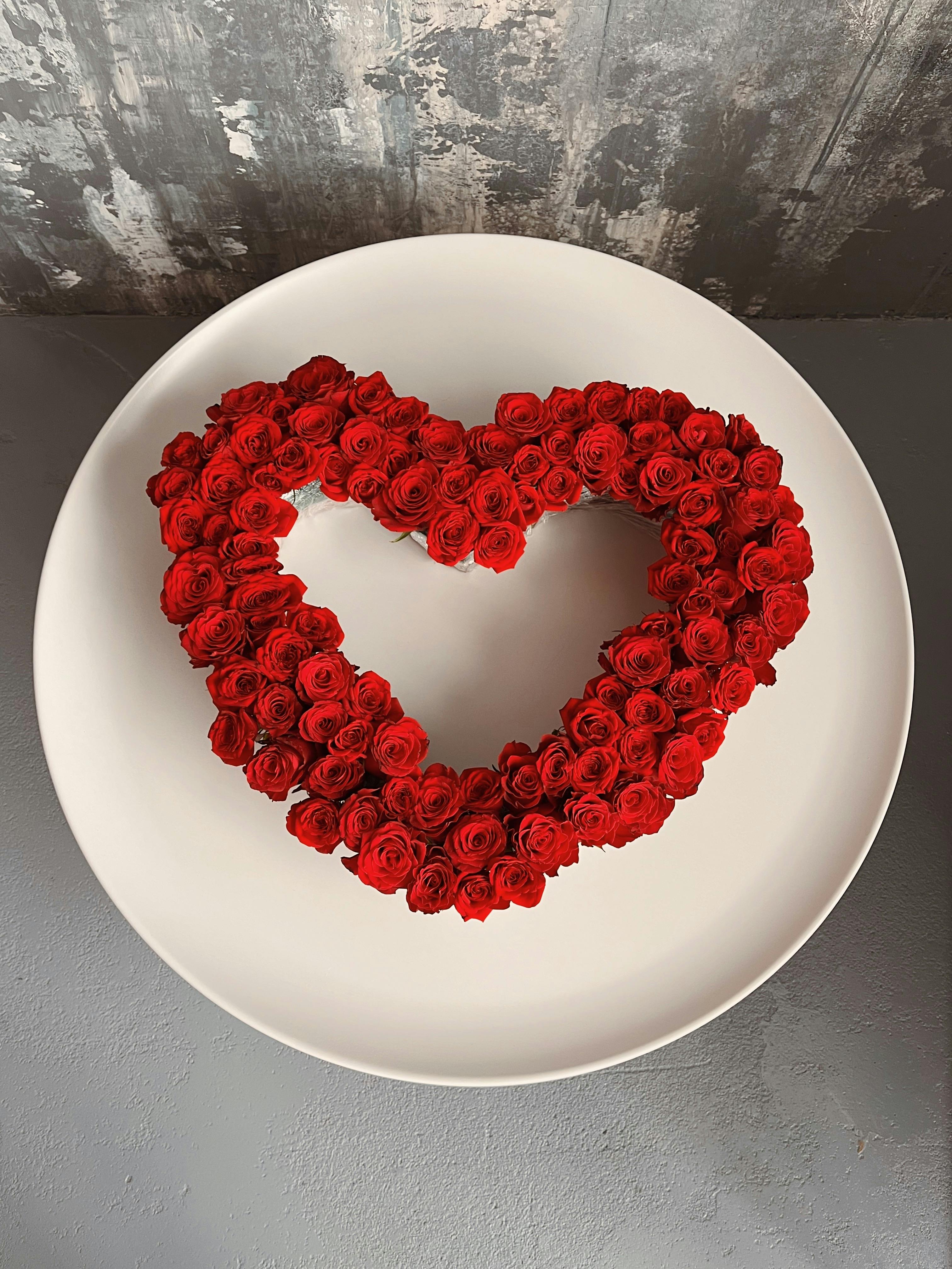 Floral heart composed of red roses on a white plate.
