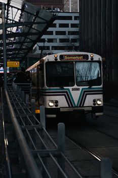 A city transit bus labeled Somerset under a canopy with urban buildings in the background.