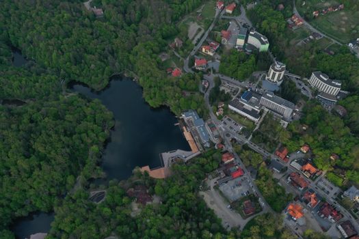 A breathtaking aerial view of Sovata, Romania, showcasing the serene lake surrounded by dense green forest and urban buildings.