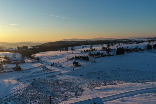 Free Captivating aerial view of Fântâna Brazilor, Harghita, Romania, with snow-covered fields at sunset. Stock Photo