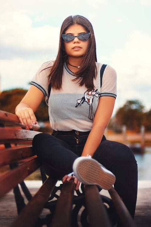 Photo of Woman in Black Sunglasses Sitting on Park Bench Posing