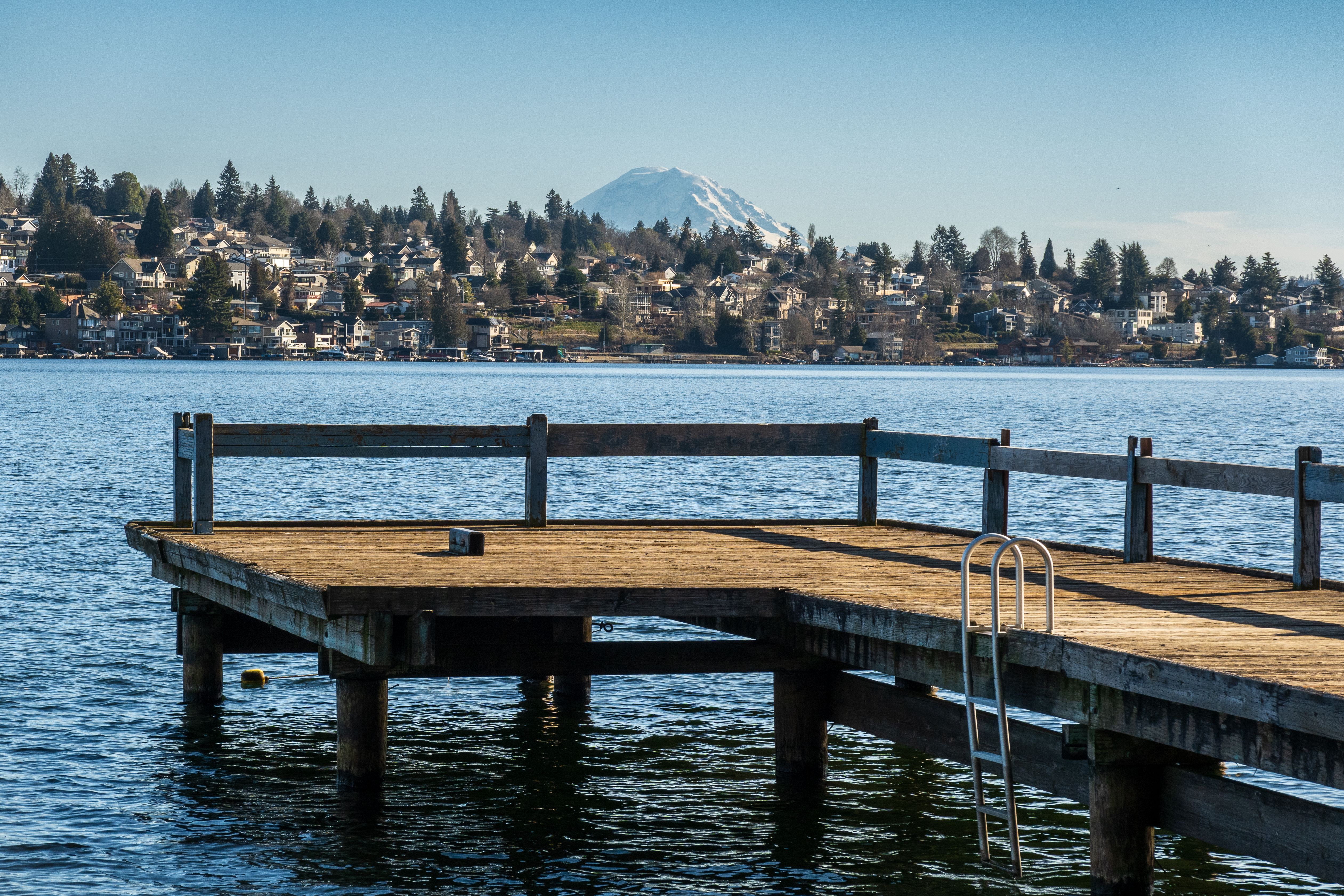 A scenic view of a pier extending into a lake with Mount Rainier in the background.