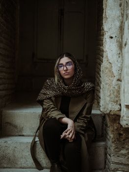 Contemplative woman sitting on stone steps, wearing a leopard print scarf.