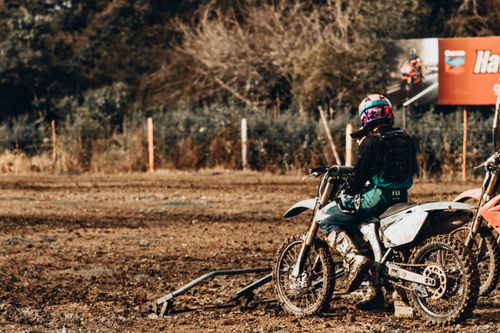 Free Back view of anonymous person in helmet parking motorbike on dirty ground on sunny day in countryside Stock Photo