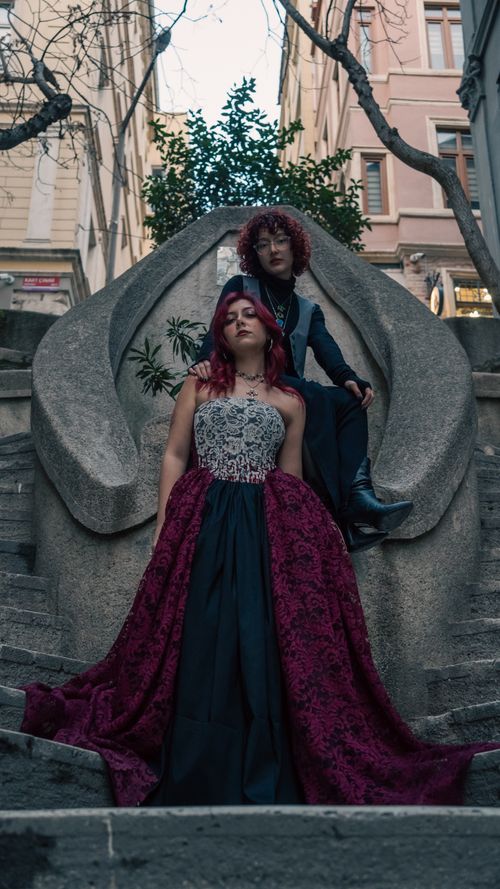Free Stylish redheaded adults in formal attire posing on urban stone stairs, evoking elegance and drama. Stock Photo