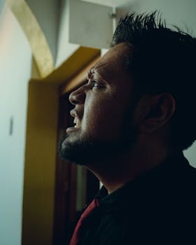 Expressive profile portrait of a man with a gothic style and dramatic lighting indoors.