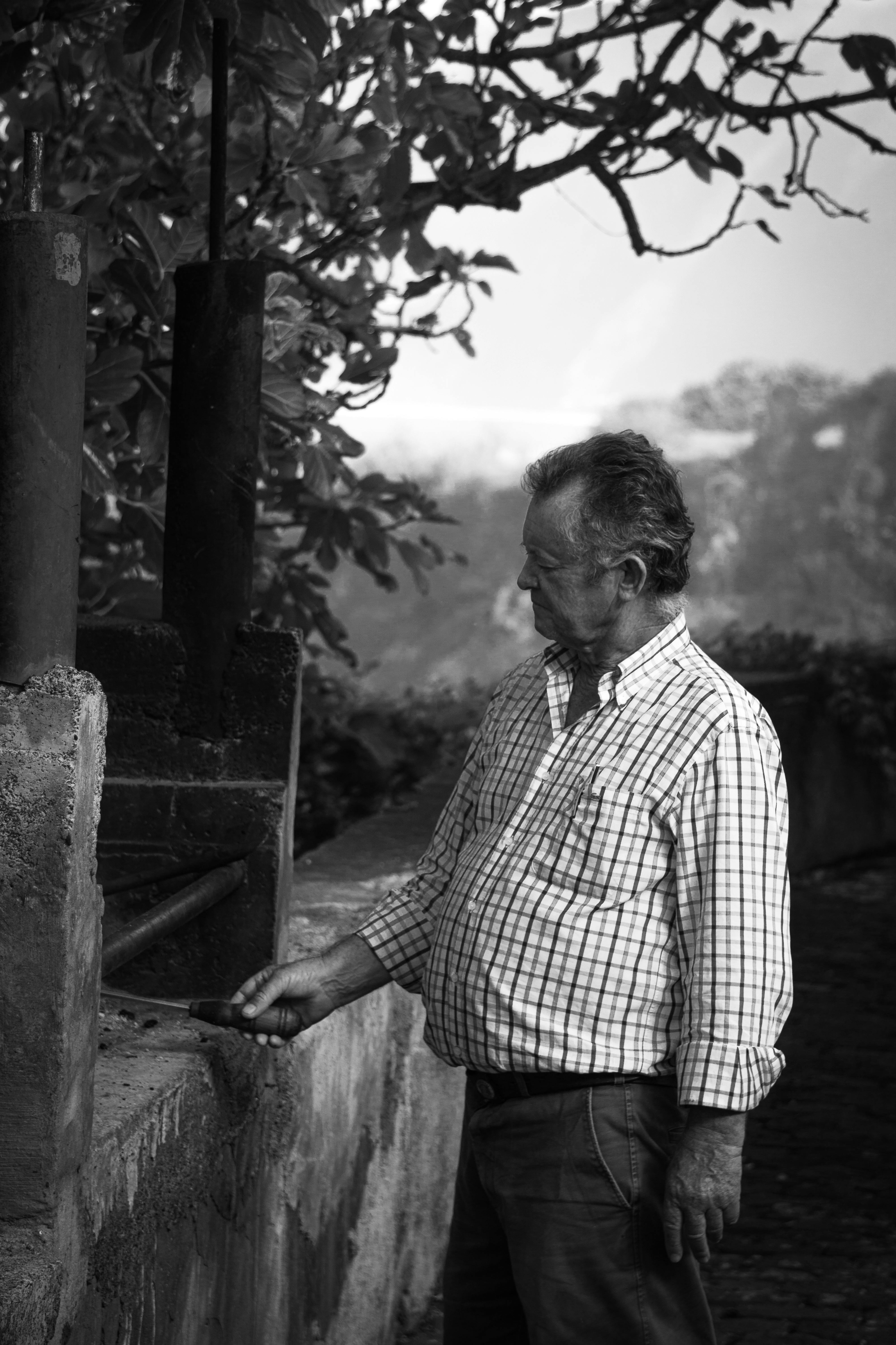 Monochrome image of an elderly man standing and relaxing outdoors in Portugal.