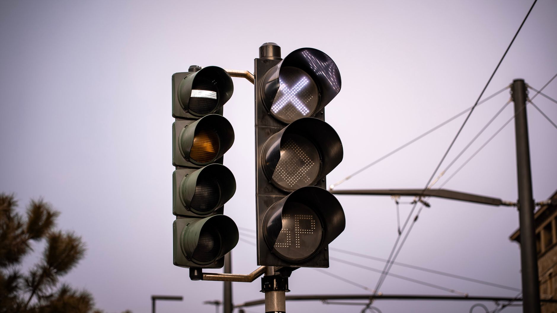Detailed view of traffic lights in Florence, Italy at dusk with a clear sky background.