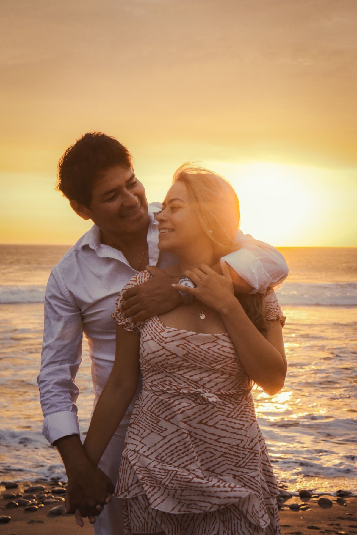 Couple enlacé sur la plage au coucher du soleil