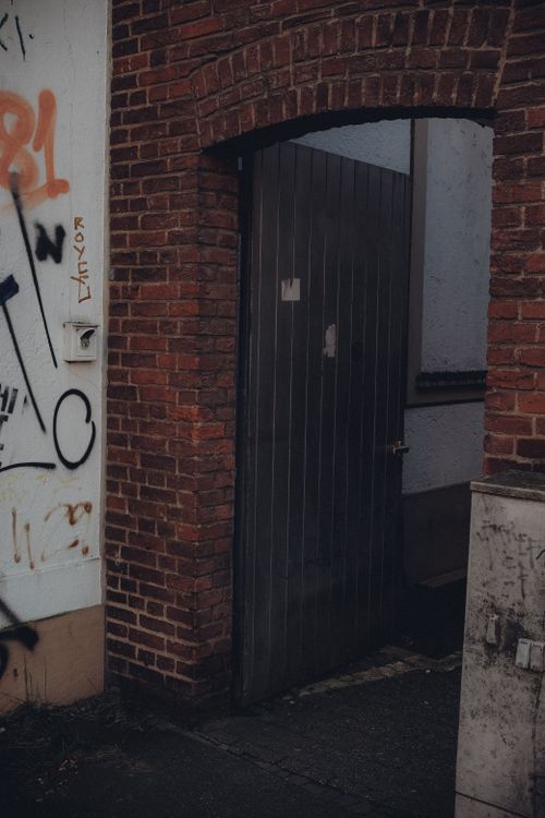 Free Moody urban scene of a brick alley with an open gate and graffiti. Stock Photo