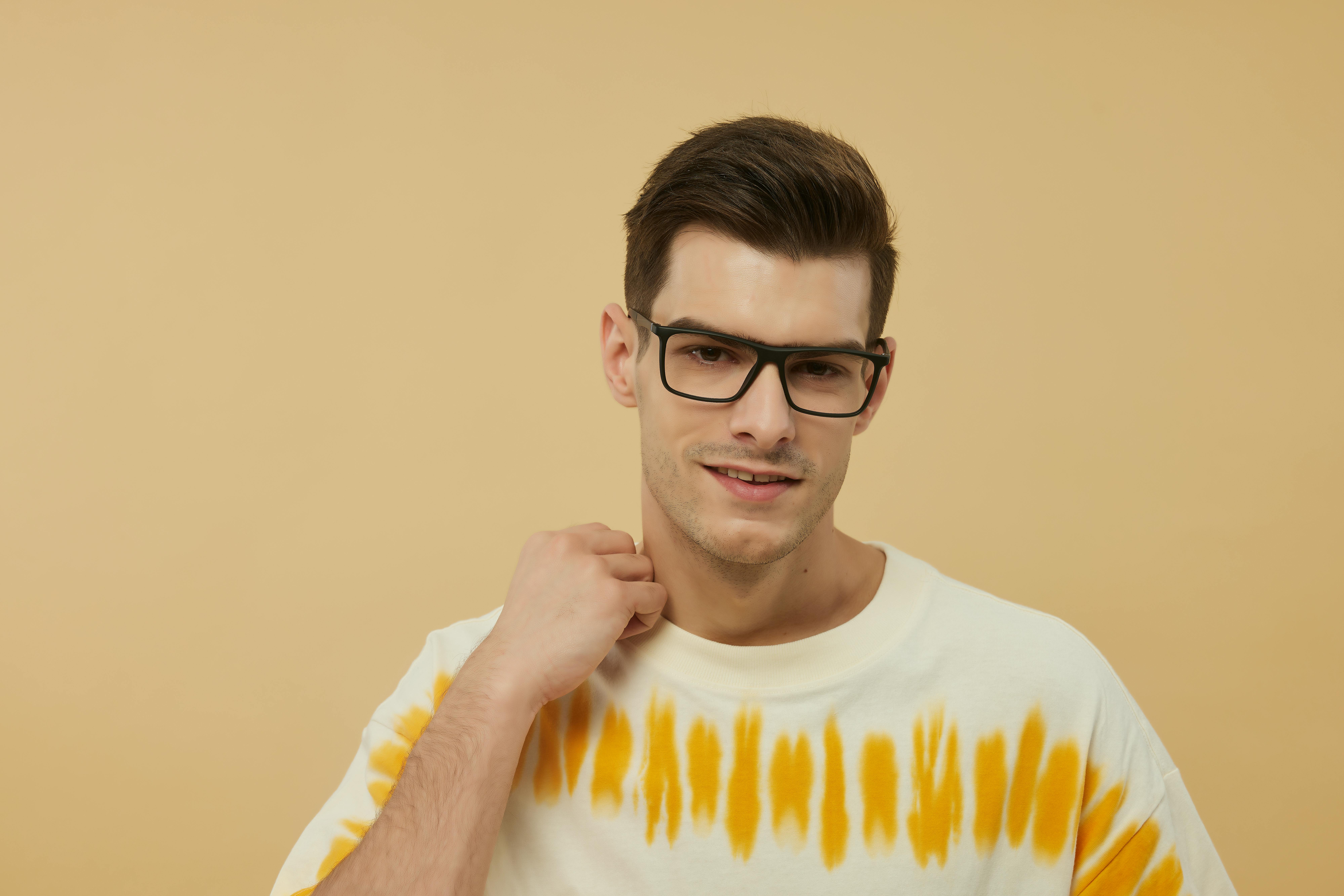 Free Confident man posing with fashionable eyewear against a warm background. Stock Photo