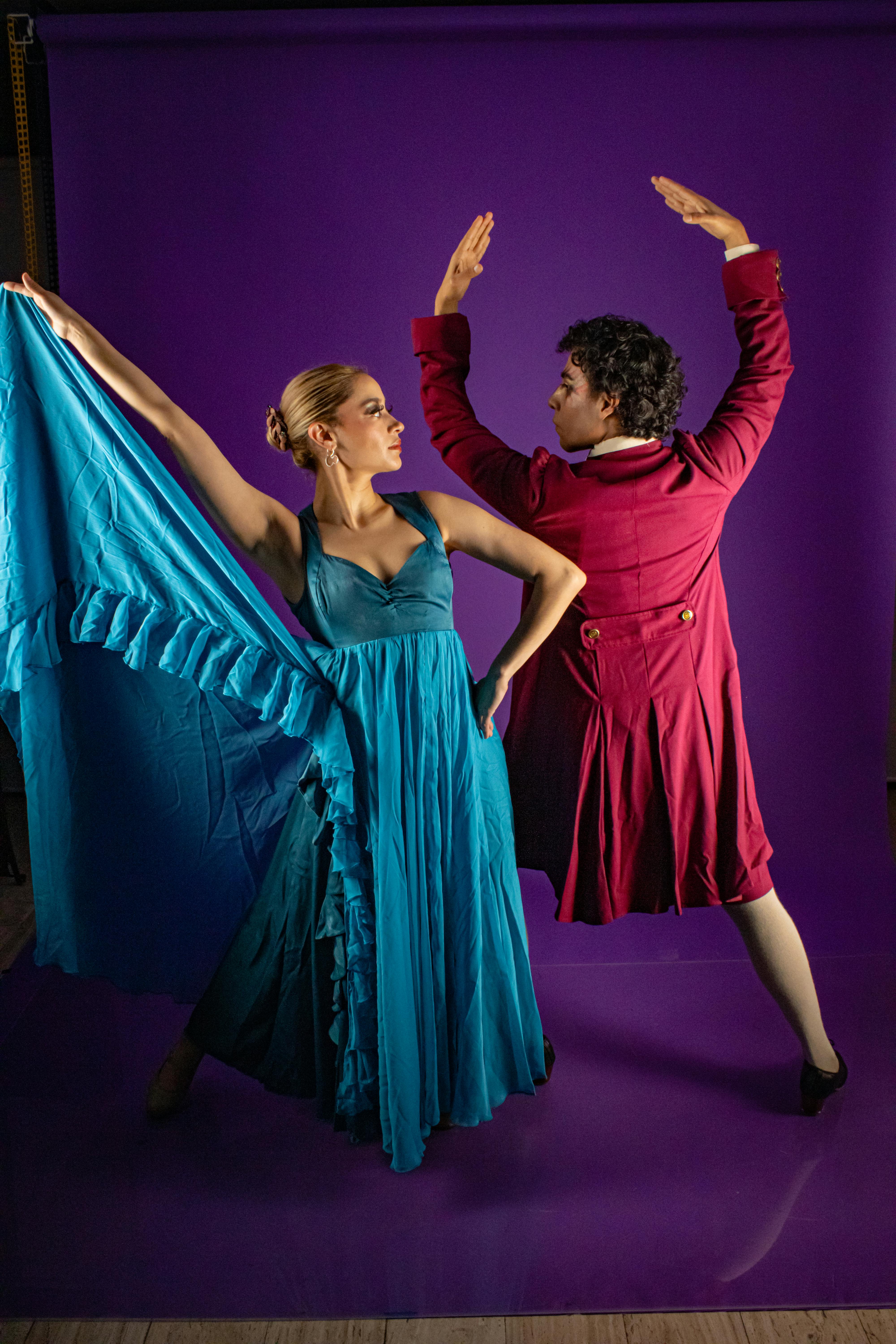 Ücretsiz İki dansçı, mor bir fon önünde renkli kıyafetlerle flamenko dansı yapıyor. Stok Fotoğraflar