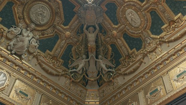 Lavishly decorated baroque ceiling with intricate sculptures in Paris.